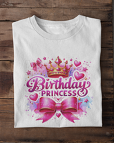 White t-shirt with 'Birthday Princess' design on a wooden surface with white sneakers.